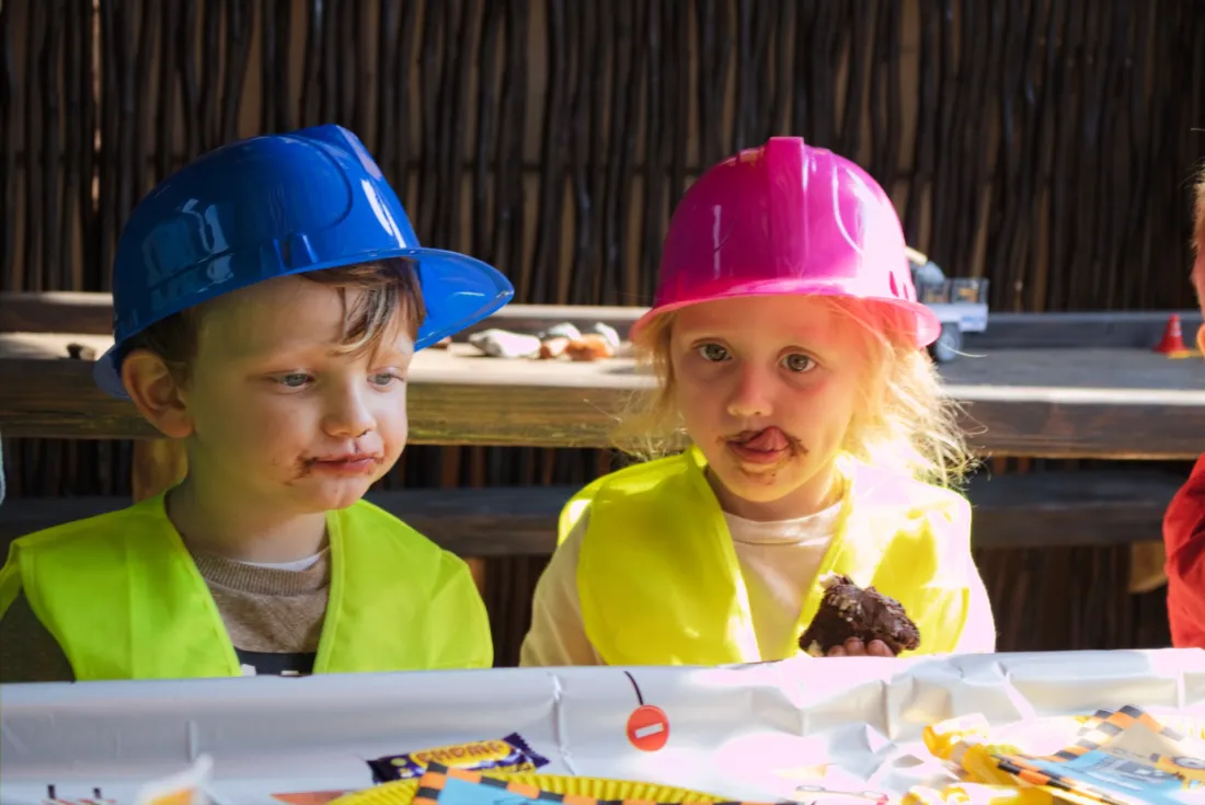 Two happy children in blue and pink hard hats and hi-vis vests at a Backyard Diggers birthday party