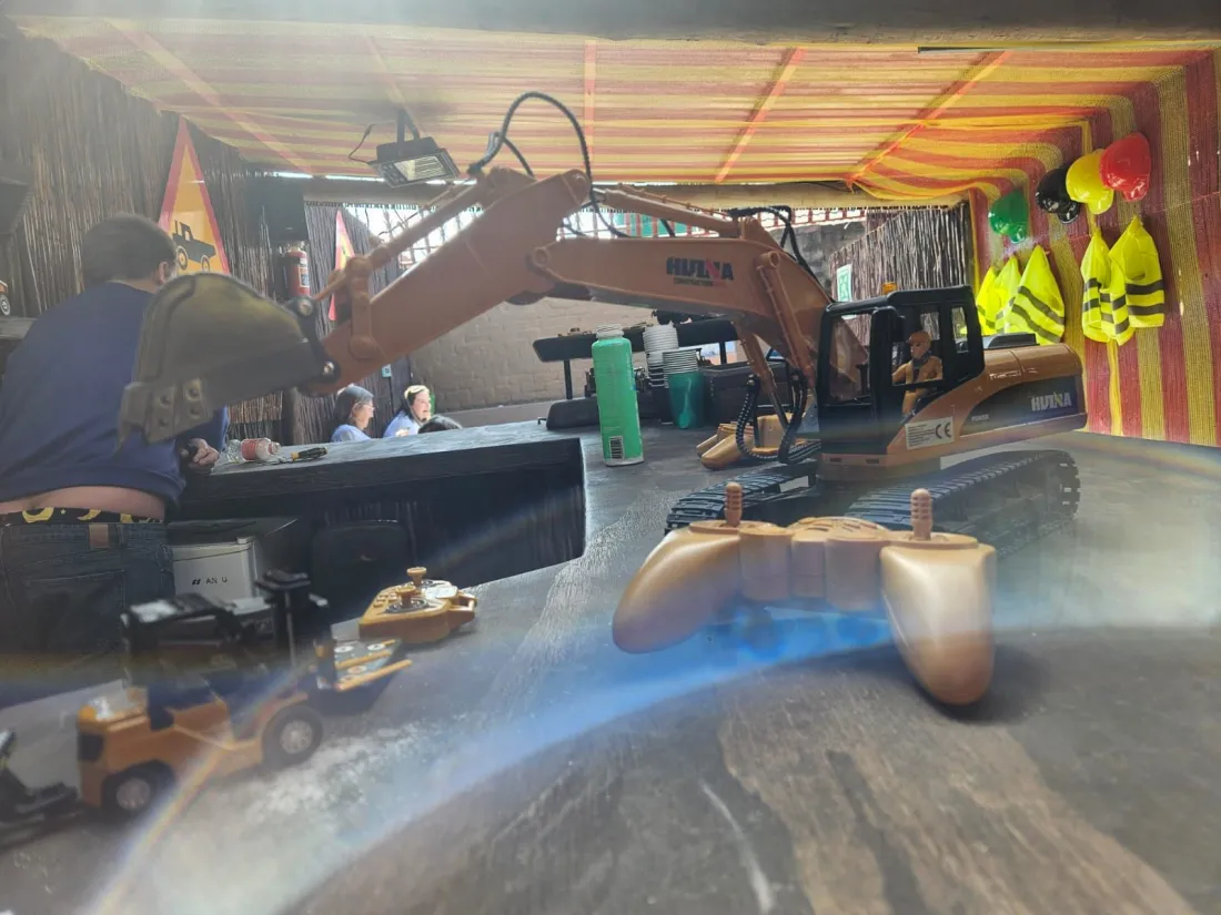 A remote-control excavator beside its controller on the play table